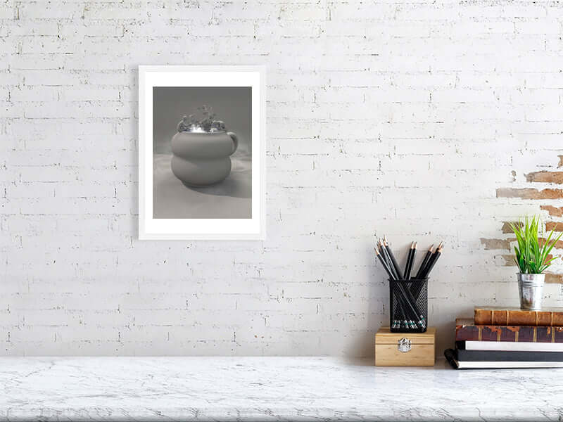 Framed digital art print of a clay cup with trippy design on a white wall above a desk with stationary and books. Modern big canvas print.